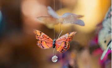Orange and black butterfly hanging as a decorative ornament against a blurred colorful background