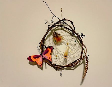 grape vines in a circle with thin string in the center for attaching three feathers and a butterfly to create a dream catcher