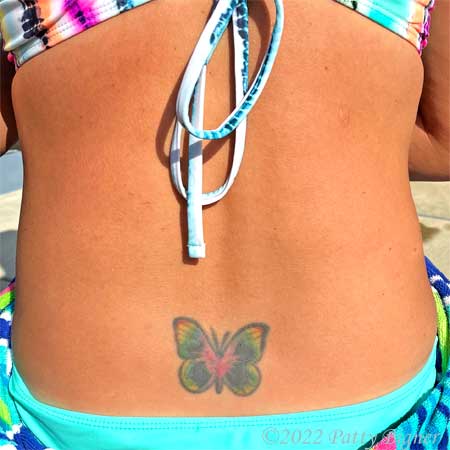 Rainbow butterfly tattoo on the lower back of a girl