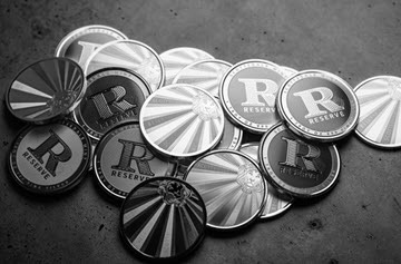 Scattered grayscale poker chips featuring an 'R Reserve' logo on a dark surface.