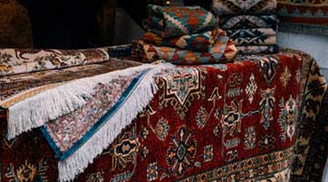 Close-up of colorful Persian-style rugs with intricate floral patterns laid over a surface on display.